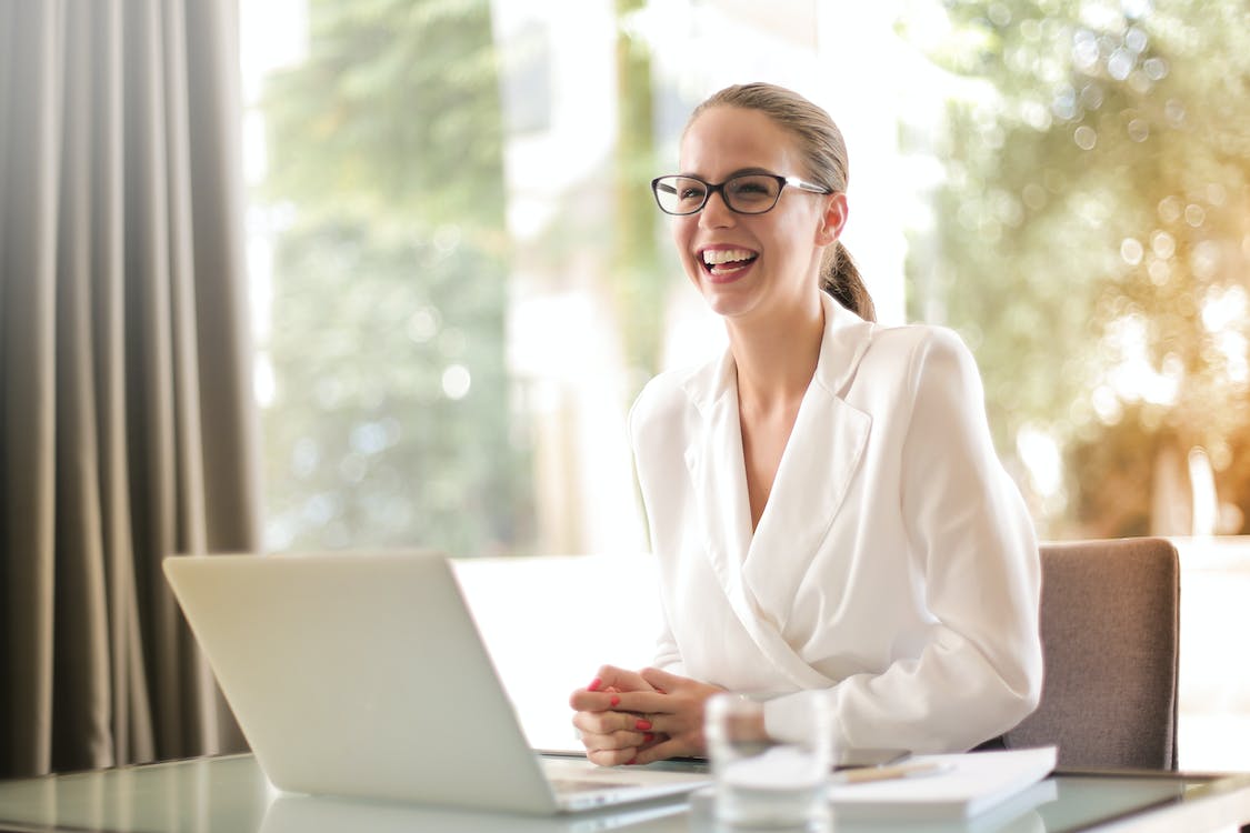 Free Laughing businesswoman working in office with laptop Stock Photo